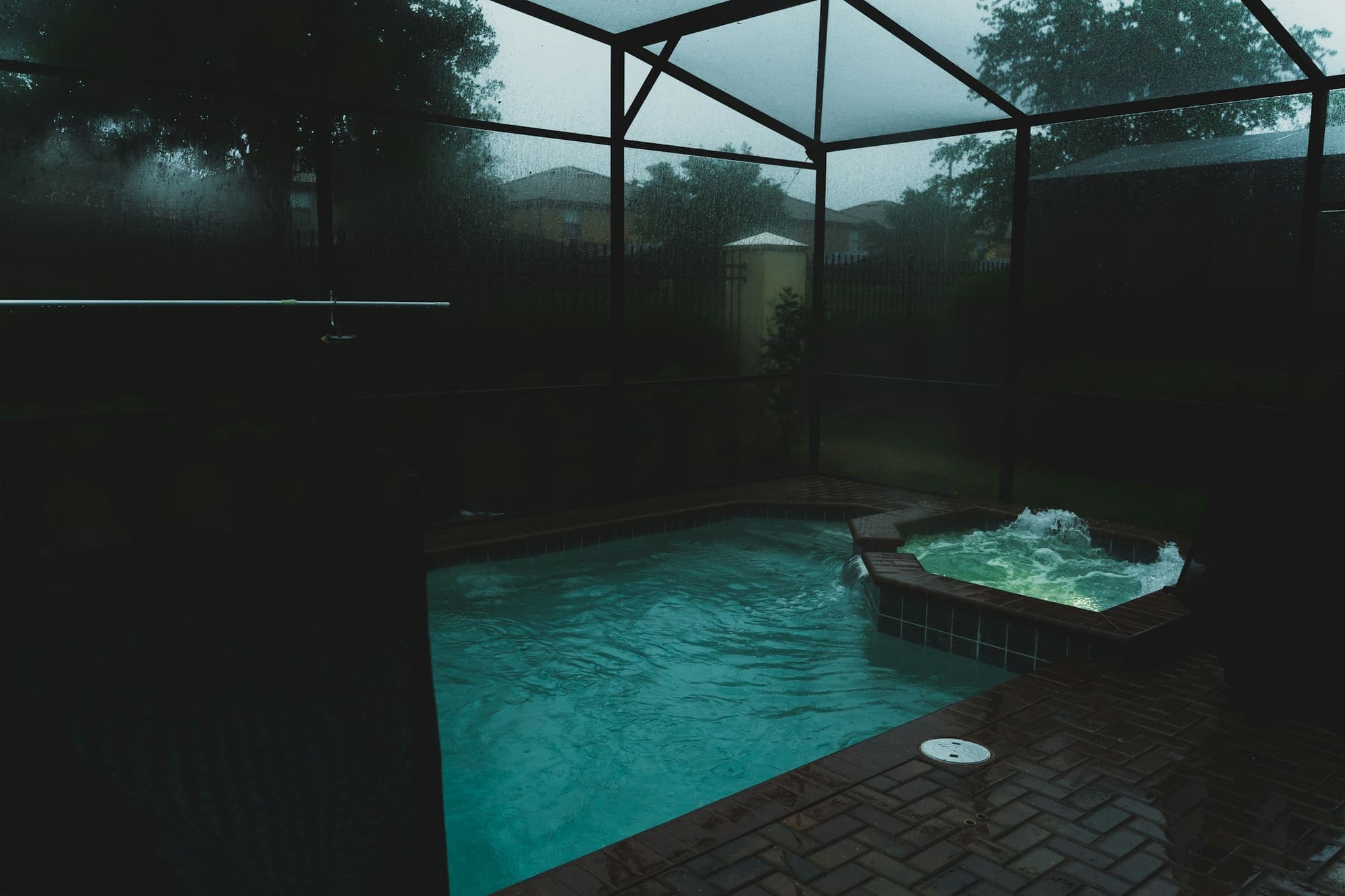Screened pool enclosure with an attached spa in the evening