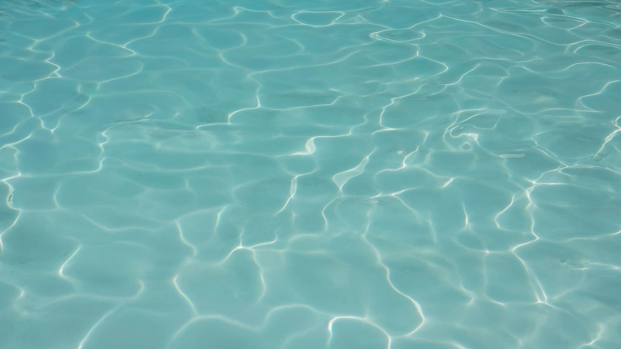 Sunlight rippling across clear turquoise pool water